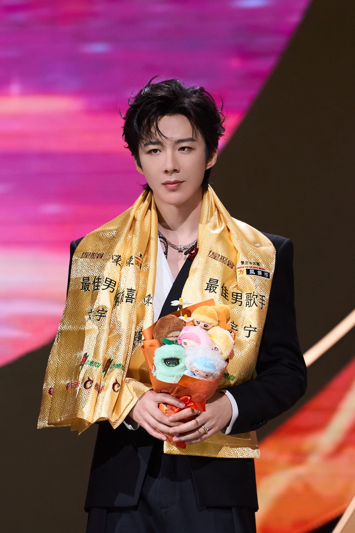 Liu Yuning wearing a Best Male Singer sash at a music awards ceremony, holding a bouquet